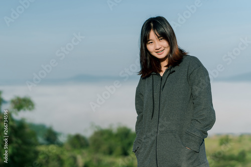 Asian woman Put on a smiling winter coat In the tourist area behind the fog and mountains with a smiling expression of happiness