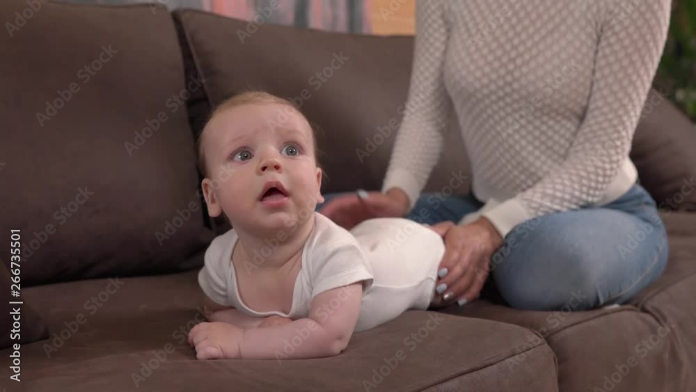 Mother and her infant baby. Adorable child lying on tummy and looking around with curiosity. Child exploring the world. Mother and her infant baby. Adorable child lying on tummy and looking around with curiosity. Child exploring the world.