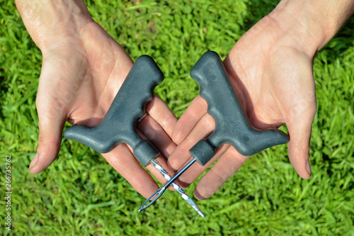 Tools for repairing punctures in tubeless tires of motorcycle or car, in hands of mechanic on background of green grass