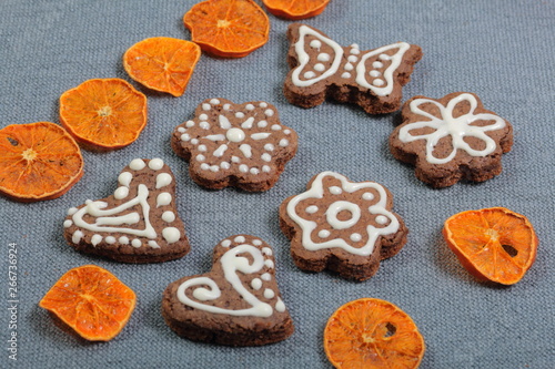 Gingerbread cookies decorated with a pattern of white glaze. On a background of gray fabric. Decorated with decorative elements of dried fruit