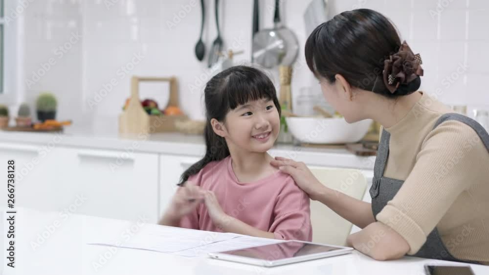 Asian mother teaches homework to daughter at home. Asian family study and learning with tablet together. Concept of education, technology, happy family and activity holiday. Asian mother teaches homework to daughter at home. Asian family study and learning with tablet together. Concept of education, technology, happy family and activity holiday.