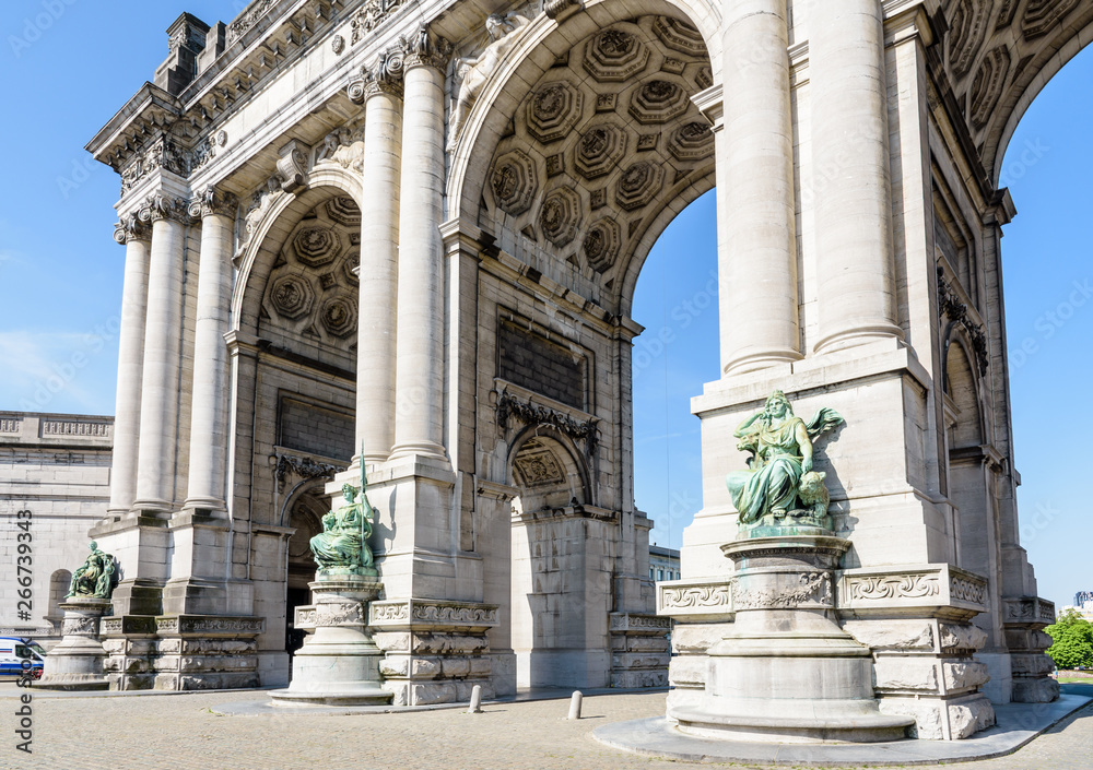 Low angle view of the eastern side of the arcade du Cinquantenaire, the triumphal arch erected in 1905 by king Leopold II in the Cinquantenaire park in Brussels, Belgium, against blue sky.