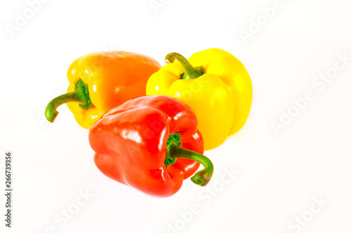 Juicy red, orange and yellow peppers with a green tail lies on a white background