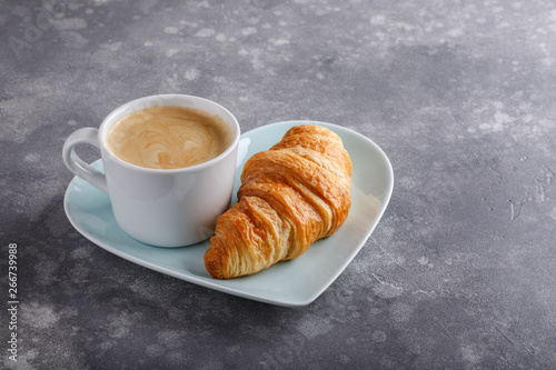 Fototapeta Naklejka Na Ścianę i Meble -  Cup of coffee and freshly baked croissants on gray background. Copy space.