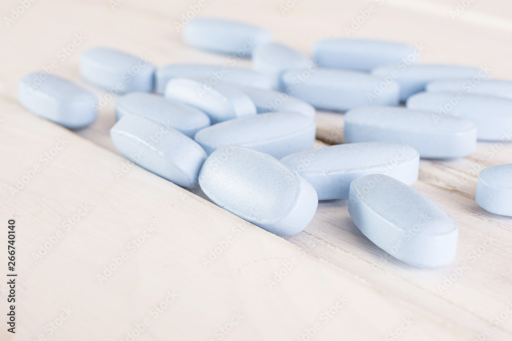 Lot of whole uncoated blue medical drug on white wood Lot of whole uncoated blue medical drug on white wood