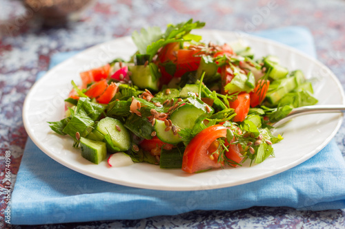 fresh salad of fresh cucumbers, tomatoes and herbs, sprinkled with flax seeds