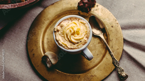 Photography A cup of coffee with vanilla cream on a golden plate with a spoon