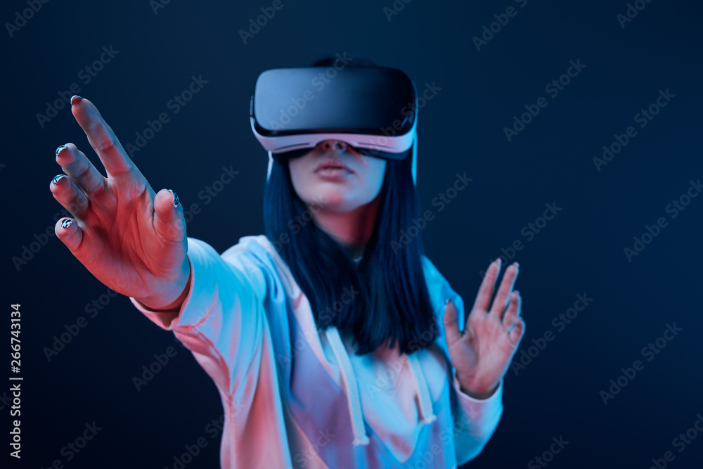 selective focus of young woman gesturing while using virtual reality headset on blue selective focus of young woman gesturing while using virtual reality headset on blue