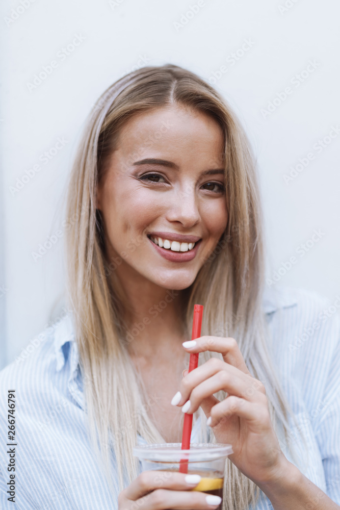 Smiling young girl drinking juice while standing Smiling young girl drinking juice while standing