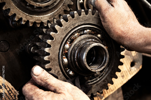 Man repairs engine of tractor, agricultural machinery. Bearing, gears, close-up.