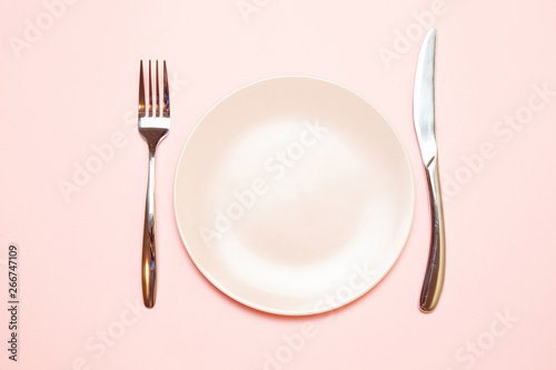 Pink empty plate with fork and knife on a pink tablecloth