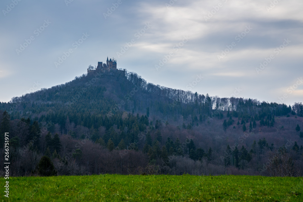 Germany, Hohenzollern castle on top of a mountain covered by forest in swabian jura countryside