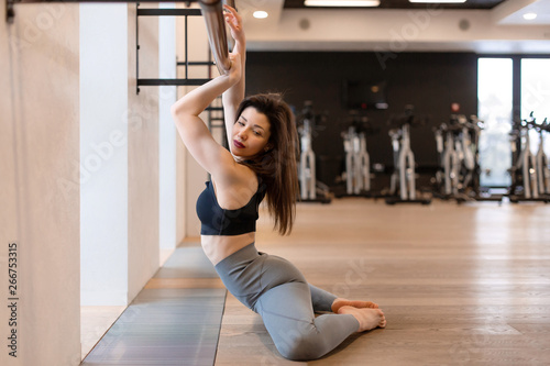 Young sexy woman doing stretching exercises in gym