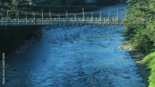 Walk bridge over a large tropical river with loads of people walking over it