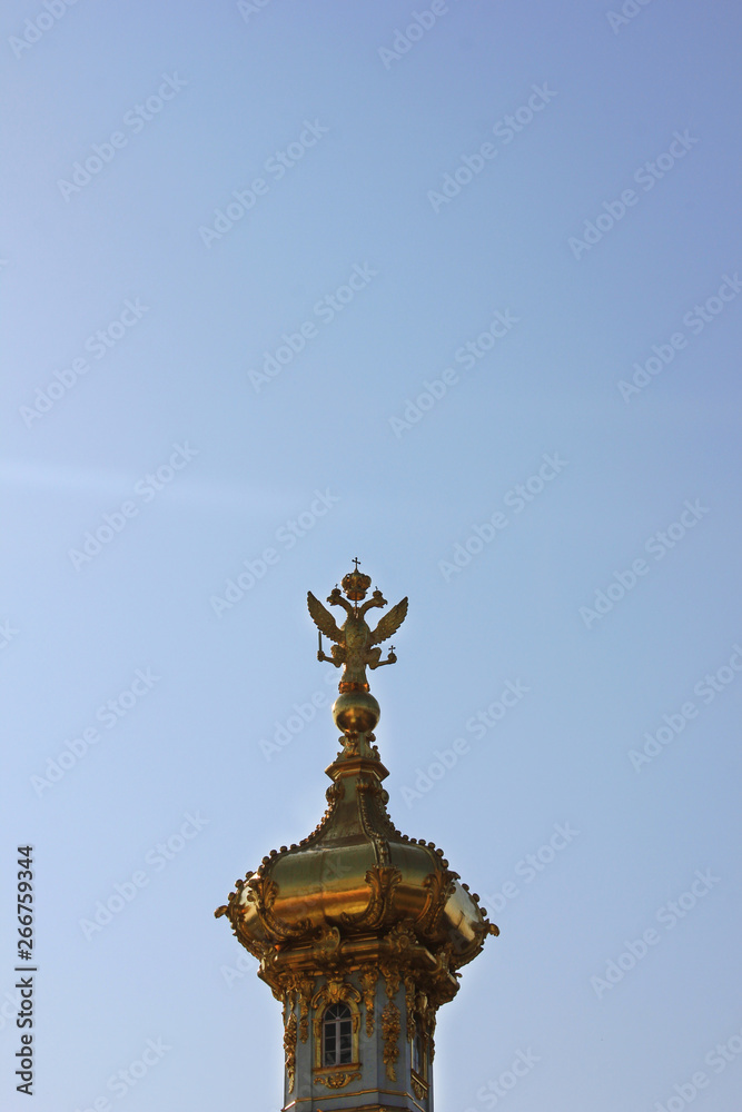 Golden dome with two headed eagle - symbol of russian empire on top. Gilded cupola close up view isolated on blue sky background Golden dome with two headed eagle - symbol of russian empire on top. Gilded cupola close up view isolated on blue sky background
