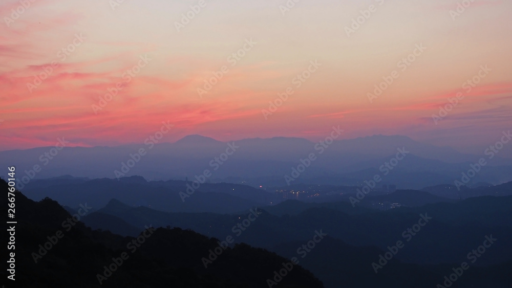 Silhouette of mountain range with beautiful layers of it's peak and orange sunset background.