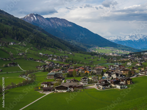 Spring mountain rural landscape. View over Stubaital Stubai Valley near Innsbruck, Austria with village Neder, green meadow, snow covered alpen mountain peaks