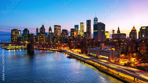 New York, USA. Aerial view on the city skyline in New York City, USA during the sunset. Famous skyscrapers of the concrete jungle and car traffic. Time-lapse of Brooklyn Bridge, zoom out
