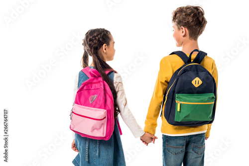 back view of schoolchildren with backpacks holding hands isolated on white