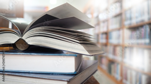Blurred image, open book page on wood desk in the library room for business and  education background, back to school concept