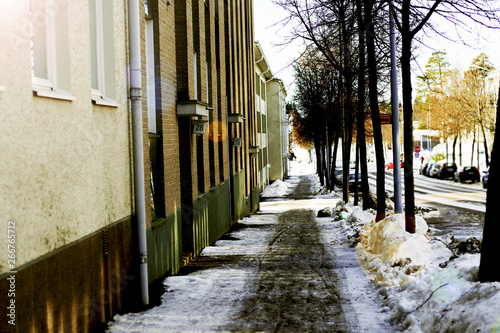 snowy european street sidewalk in the city along a beige brick building in winter