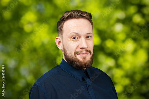 Portrait of handsome adult man on green bokeh background. Caucasian man with beard smiling. Businessman.