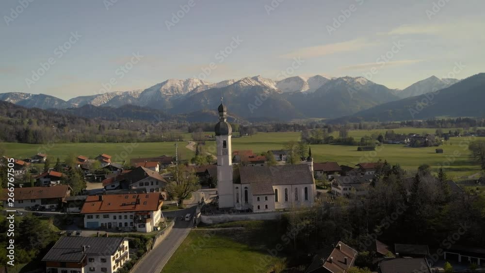Flight over authentic old church in Bavarian village with beautiful alps in the background Flight over authentic old church in Bavarian village with beautiful alps in the background