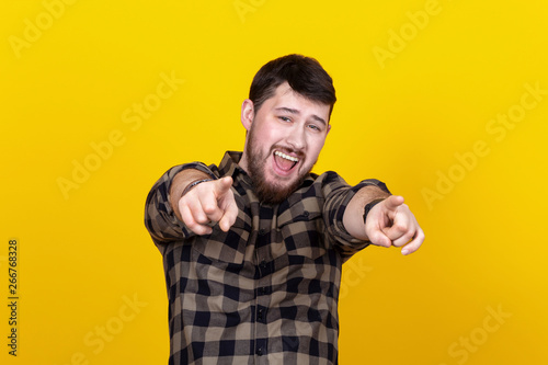 Handsome bearded man pointing at viewer over yellow background