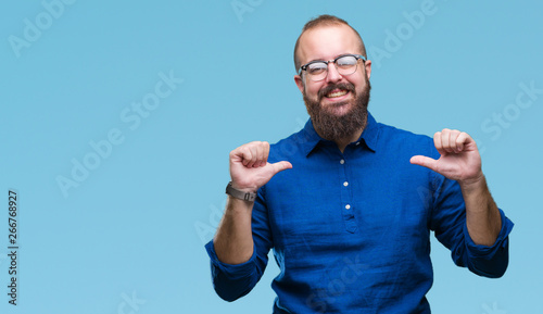 Young caucasian hipster man wearing glasses over isolated background looking confident with smile on face, pointing oneself with fingers proud and happy. photo