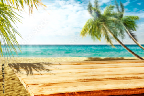 Wooden table background of free space and summer beach with palms.  © magdal3na