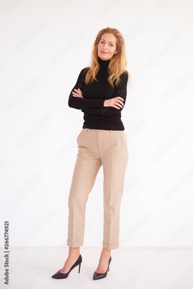 Full length shot of blond middle aged woman while standing at isolated white background Full length shot of blond middle aged woman while standing at isolated white background