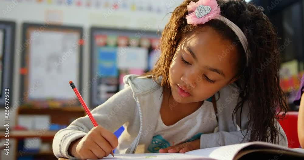 Front view of African american schoolgirl drawing on notebook in the classroom 4k