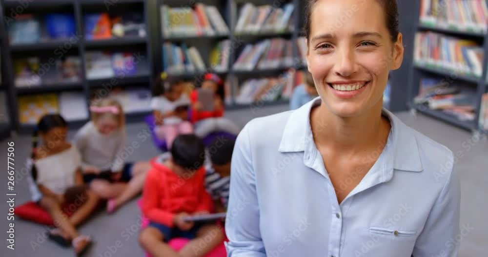 Front view of happy Caucasian female teacher standing in the school library 4k