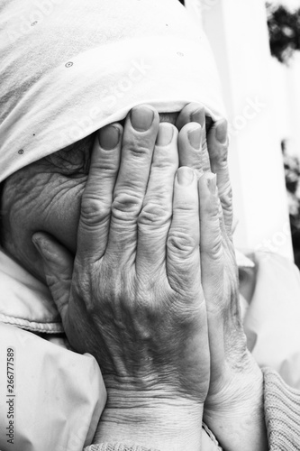 Senior woman closed face by palms. Black and white photography