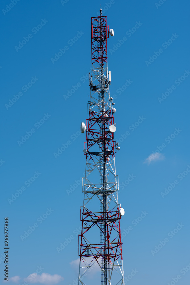 Communication tower on the green field against clean blue sky