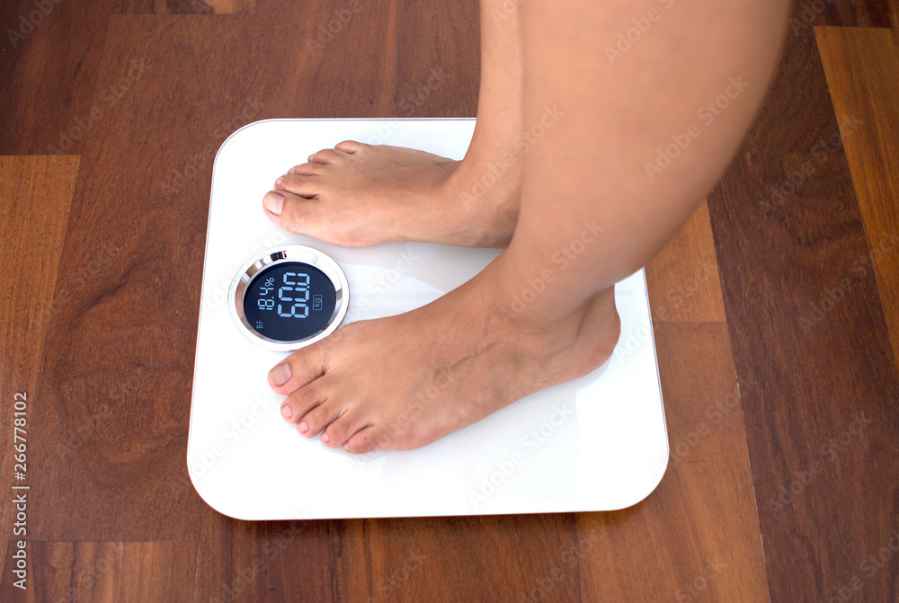 Bare feet stand on smart scales that makes bioelectric impedance analysis,  BIA, body fat measurement. Stock Photo by ©akoldunov 369502604