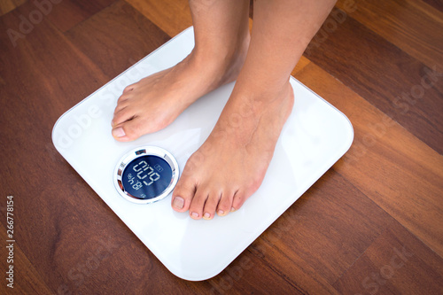 Woman bare feet standing on a digital scale with body fat analyzer that uses bioelectrical impedance (BIA) to gauge the amount of fat in your body