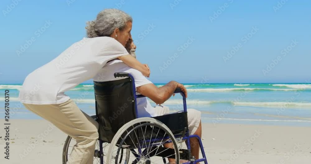 Side view of active senior African American woman embracing disabled senior man on the beach 4k Side view of active senior African American woman embracing disabled senior man on the beach 4k