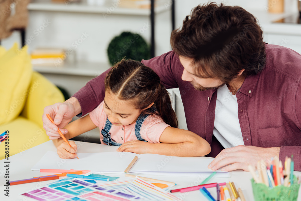 bearded father helping cute daughter drawing on paper bearded father helping cute daughter drawing on paper