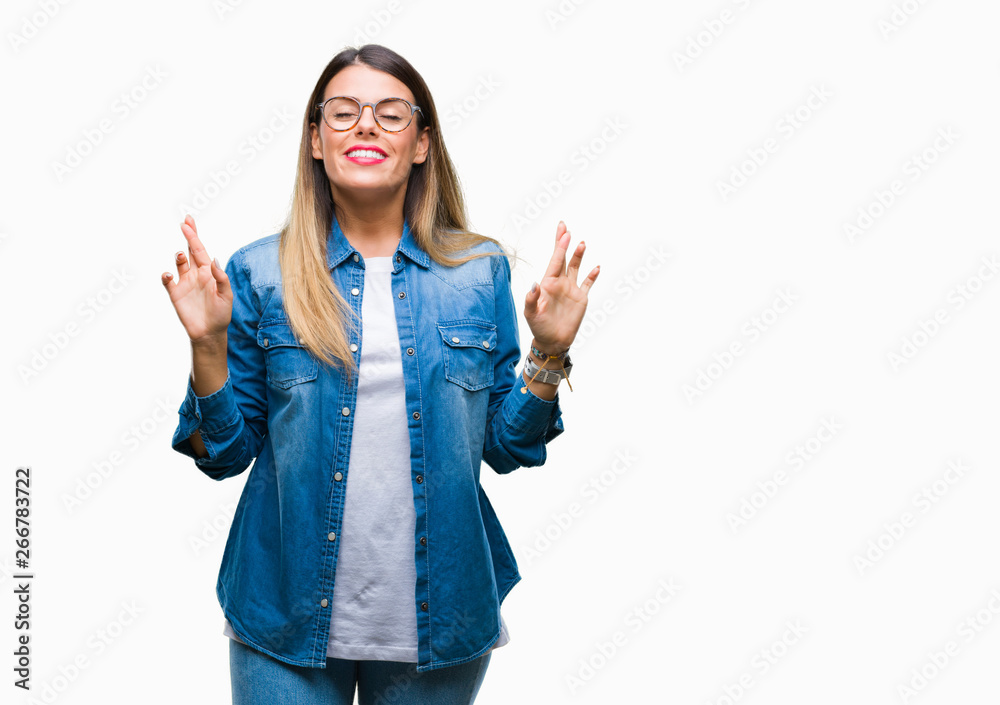 Young beautiful woman over wearing glasses over isolated background smiling crossing fingers with hope and eyes closed. Luck and superstitious concept. Young beautiful woman over wearing glasses over isolated background smiling crossing fingers with hope and eyes closed. Luck and superstitious concept.