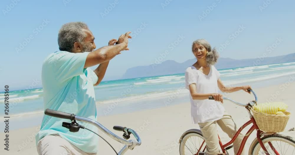 Side view of active senior African American man taking photo of woman with mobile phone at beach 4k Side view of active senior African American man taking photo of woman with mobile phone at beach 4k