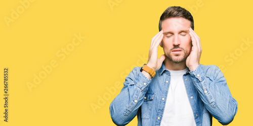 Handsome man with blue eyes and beard wearing denim jacket with hand on head for pain in head because stress. Suffering migraine. © Krakenimages.com