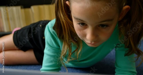 Front view of attentive Caucasian schoolgirl studying with laptop in library at school 4k