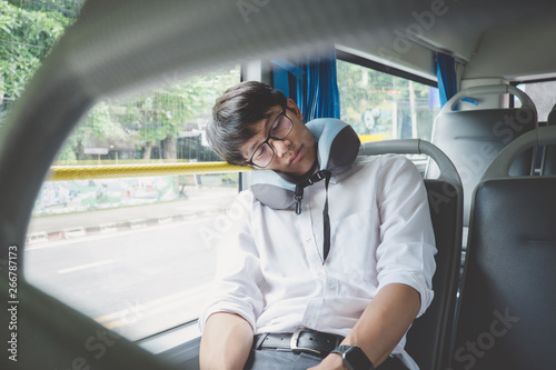 Young Asian man traveler sitting on a bus and sleeping with pillow, transport, tourism and road trip concept © Freedomz