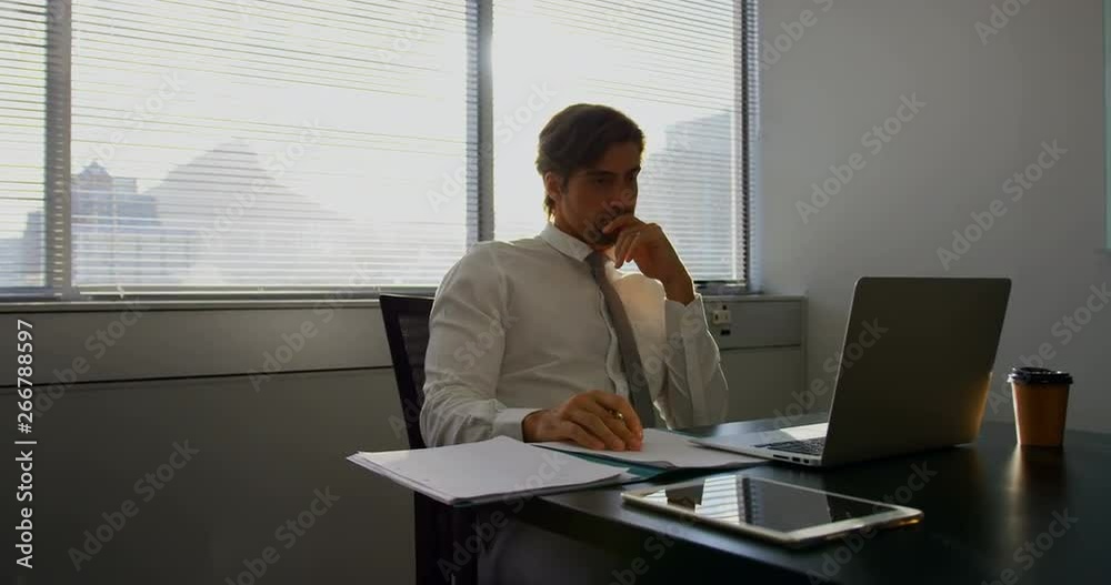 Front view of young Caucasian male executive working on laptop at desk in a modern office 4k Front view of young Caucasian male executive working on laptop at desk in a modern office 4k