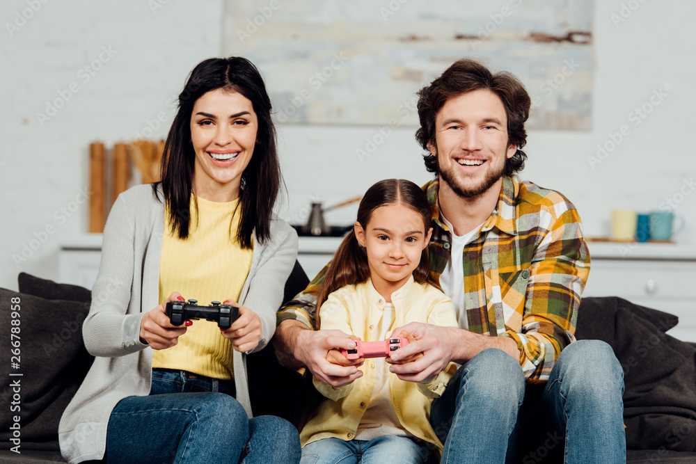 Obraz premium handsome man sitting near happy kid and playing video game at home