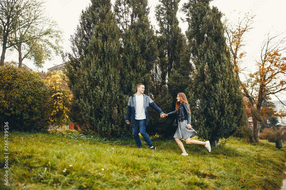 Cute couple walking in a autumn park. Boy and girl have fun