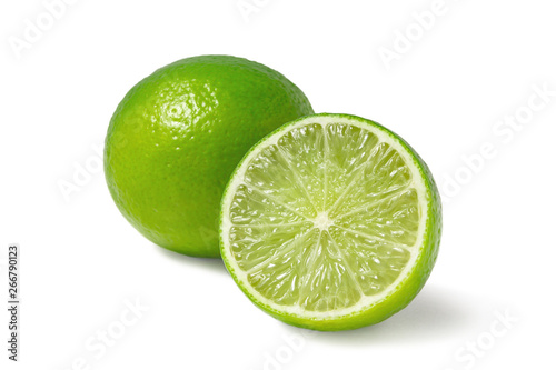 Fresh ripe limes, one whole and one half isolated on white background with shadow - image