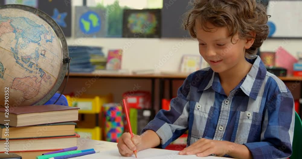 Front view of Caucasian schoolboy studying on desk in classroom at school 4k Front view of Caucasian schoolboy studying on desk in classroom at school 4k