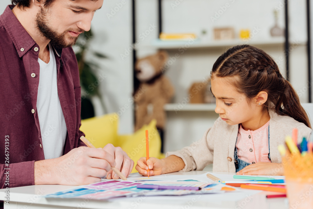 selective focus of cute daughter drawing with handsome father